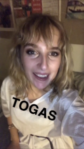 Me smiling in my toga outfit (a white oversized t-shirt with the word TOGAS in black capitals)