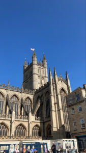 Picture of a sand-stone coloured church, called the Bath Abbey, against a blue sky.