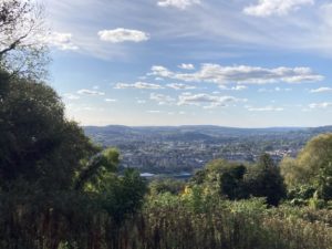 View of Bath from mountain top, surrounded by grass, trees and hills.