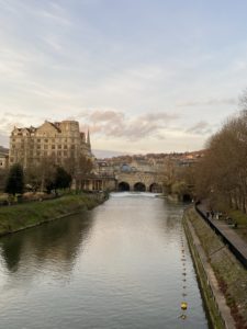 Picture of a bridge and buildings in the distance with a calming river flowing underneath it.