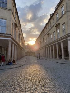 A cobble stone street with tall, columned buildings on either side of it.