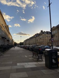 A wide street with sand-stone buildings on either sides of it.