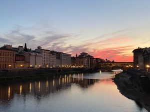 Landscape picture of a river with buildings in the background at dusk.