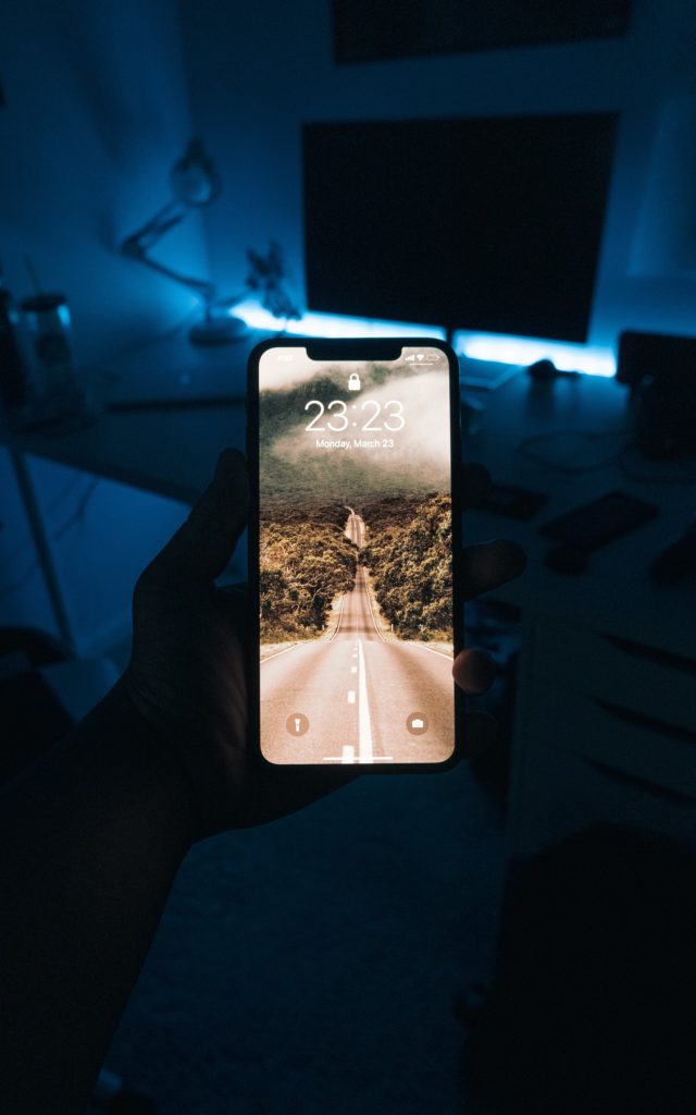 Photo of phone in someone's hand being used at night in a bedroom.