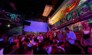 Lots of people in a Hong Kong nightclub with a big screen in the background