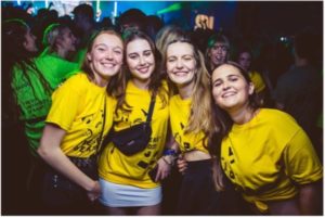 Four females in bright yellow t-shirts on a night out during Freshers' Week