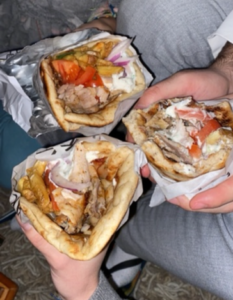 It is a close up of mine and my flatmates hands holding three Souvlaki wraps.