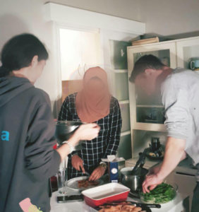 Three friends are over a table cooking.