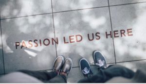 Two pairs of feet on a grey pavement which says 'Passion led us here'