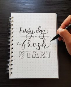 A white, spiral-bound note pad which says 'Everyday is a fresh start'