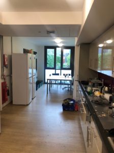 The kitchen including the fridge freezers, and the dining table with double door in the background