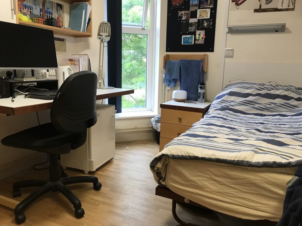 Brendon Court Room, with a bed to the right, desk on the left, and narrow window in the middle.