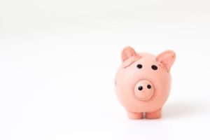 A white background, with a pink piggy bank facing the camera