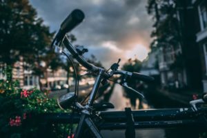 A bike resting on abridge of a canal at sunset