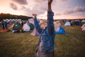 Lady dancing at a festival with camping tents in the background