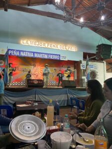 View from the audience of a stage with people playing various instruments and singing.