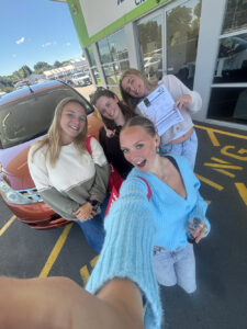 Selfie of 4 women (Grace and friends) in front of a red car