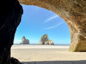 View of a sandy beach from underneath a natural rock archway