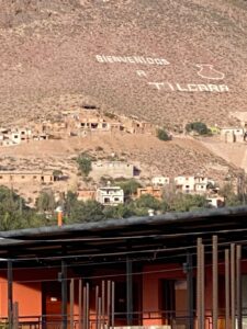 Distant view of a sandy hill, with the text 'Bienvenioos a Tilcara' written in the ground