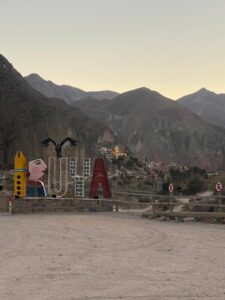 Art-deco style sign that reads: 'Iruya', with a hilly landscape in the background