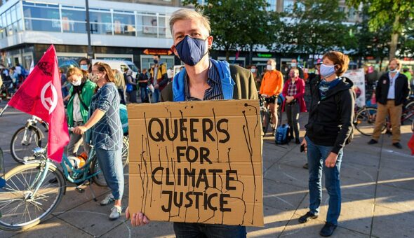 Person holding sign "Queers for Climate Justice"