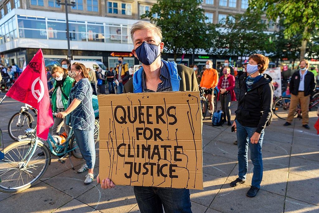 Person holding sign "Queers for Climate Justice"