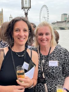 Agnes and Katherine smiling at camera holding a drink in front of the London Eye