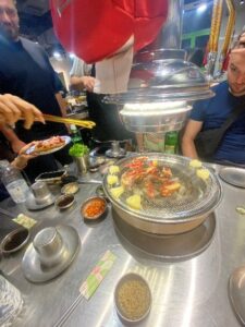 Pineapple and meat cooking on BBQ in middle of restaurant table