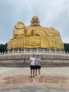 Me and a friend in front of the golden maitreya buddha statue on thousand buddha mountain